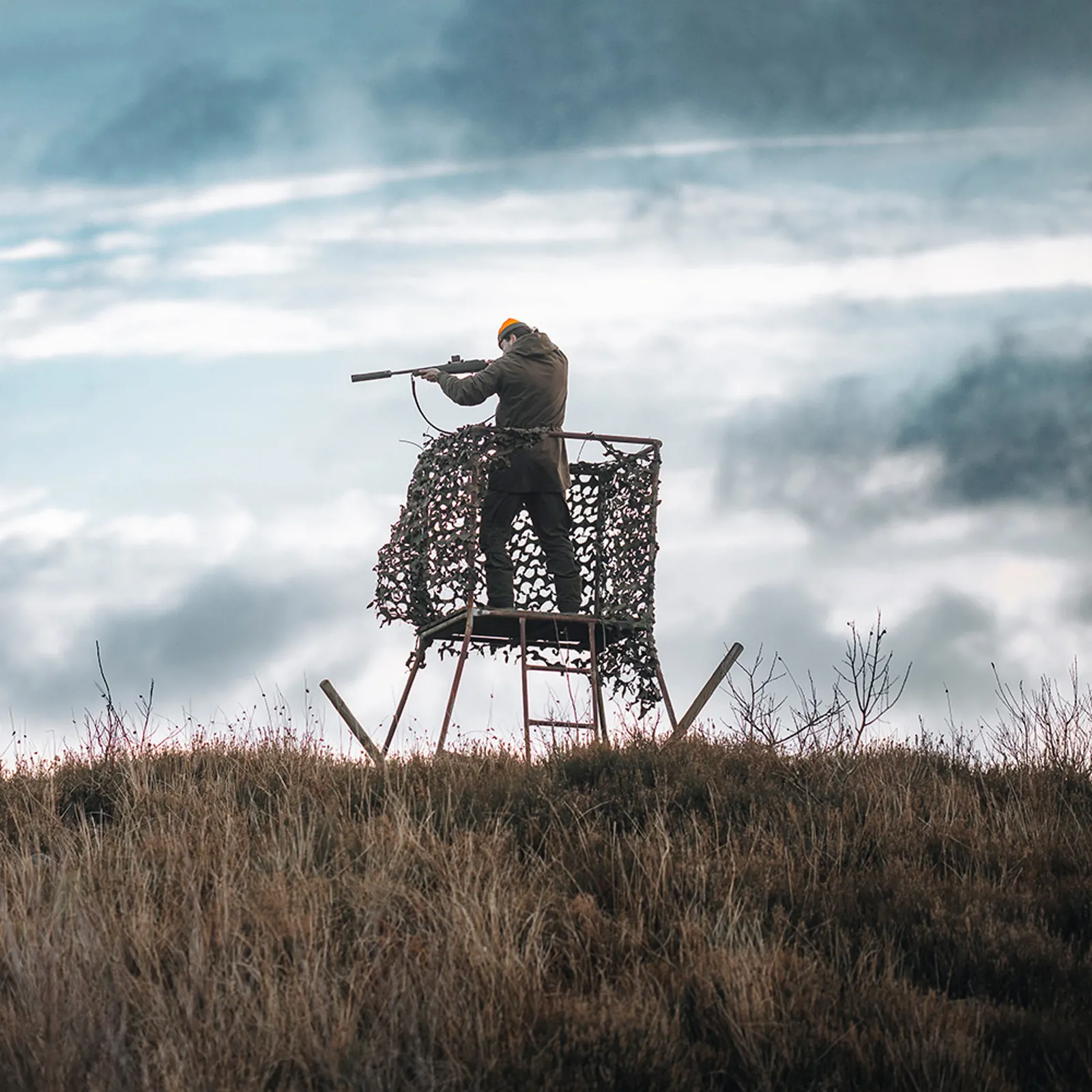 Hunter on stand aiming with a rifle