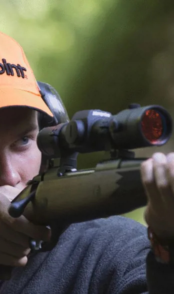 A man aiming with a rifle in the forest